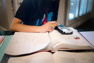 closeup of young female student doing algebra homework with a graphing calculator at kitchen counter