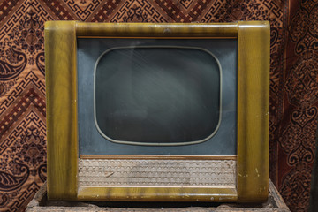 Old antique brown television with oval shaped screen sitting in front of retro wall
