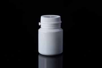 White plastic medical container on white, black background..pill bottle
