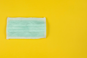 medical  face mask on yellow background. white and green medical mask for protect droplets infectious disease from infectious people.