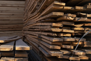 Wooden boards, lumber, industrial wood, timber. Pine wood timber stack of natural rough wooden boards on building site. Industrial timber building materials