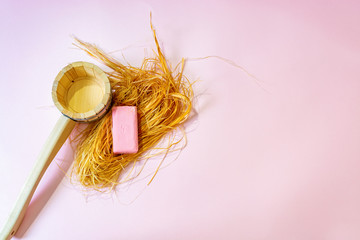 Ladle, washcloth and bath soap on a pink background