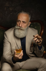 Stylish handsome bearded man holding glass of whiskey.