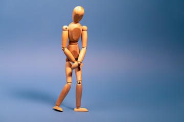 Wooden man with bladder control problem on blue background