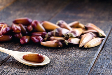 Brazilian pine nut peeled and cooked in an old wooden spoon. Rustic table, healthy and vegan cuisine.