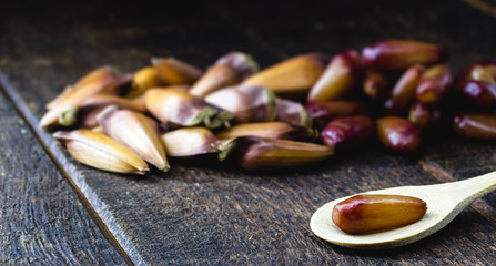 Brazilian pine nut peeled and cooked in an old wooden spoon. Rustic table, healthy and vegan cuisine.