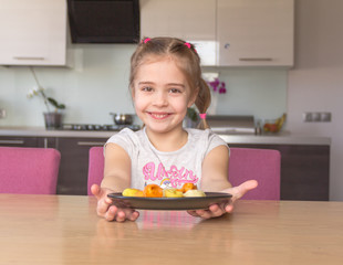 Little girl  holding plate with colorful dumplings. Coronavirus quarantine concept. Stay at home.