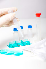 tube chemical dropper and mask in a laboratory on white grey background, hand in gloves