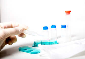 tube chemical dropper and mask in a laboratory on white grey background, hand in gloves