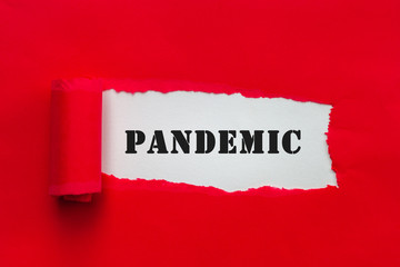 Torn red paper revealing word Pandemic. Covid-19 outbreak concept.