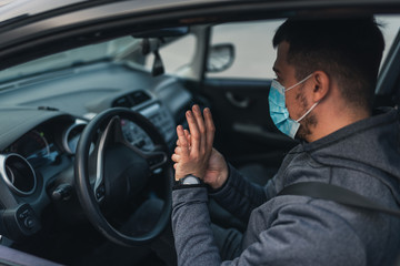 A man sits car and washes his hands with antiseptic gel. healthcare concept in car. The mask is white on the face. coronavirus, disease, infection, quarantine, covid-19