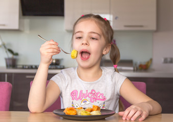 Little girl eats colorful dumplings. Coronavirus quarantine concept. Stay at home.