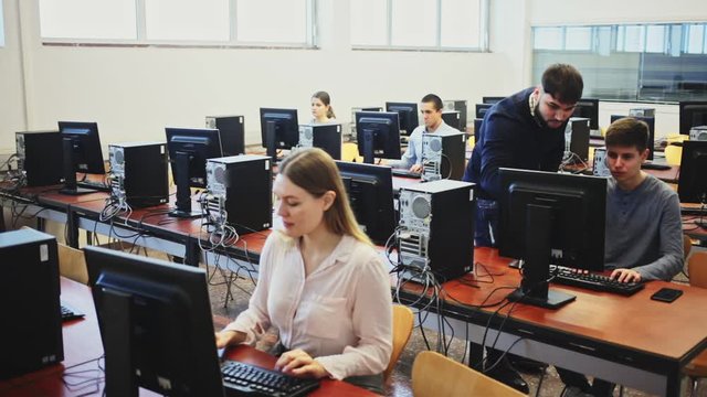 Friendly male teacher lecturing attentive adult students in computer room