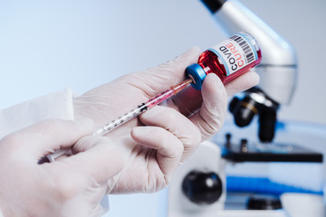 The nurse gets the vaccine into the syringe. Glass medical bottle in a doctor's hand. A bottle with...
