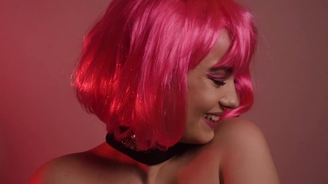 Girl with pink short hair. A model with long pink earrings and makeup. The girl in the video laughs, flirts, poses, dances, touches her hair, goes crazy. Fashion video portrait