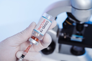 Glass medical bottle in a microbiologist's hand. A bottle with a cure holds a hand in silicone...