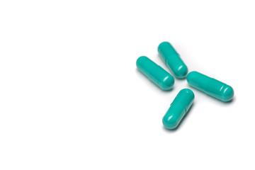 Green pills in capsules on a white table.
