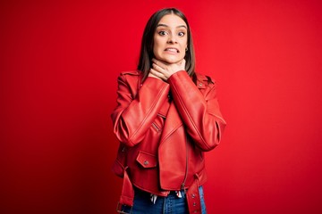 Young beautiful brunette woman wearing casual jacket standing over red background shouting and suffocate because painful strangle. Health problem. Asphyxiate and suicide concept.