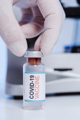 Glass medical bottle in a doctor's hand. A bottle with a vaccine holds a hand in silicone gloves in...
