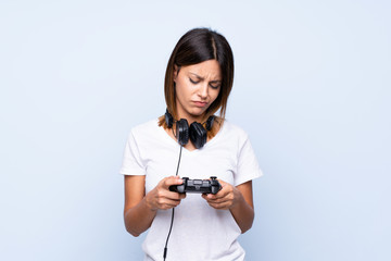 Young woman over isolated blue background playing at videogames