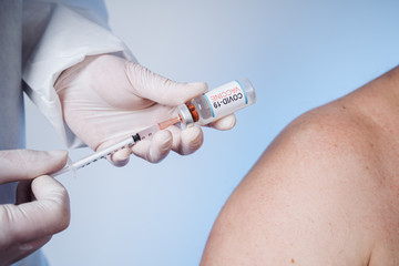 The medic gets the vaccine into the syringe. Glass medical bottle in a doctor's hand. A bottle with...