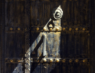 Traditional wooden door with old metal doorknocker decorated and light and shadow background,...