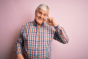 Senior handsome hoary man wearing casual colorful shirt over isolated pink background Smiling...