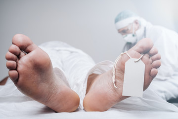 Doctor depressed after the death of another patient. Feet of a dead body, with an identification...