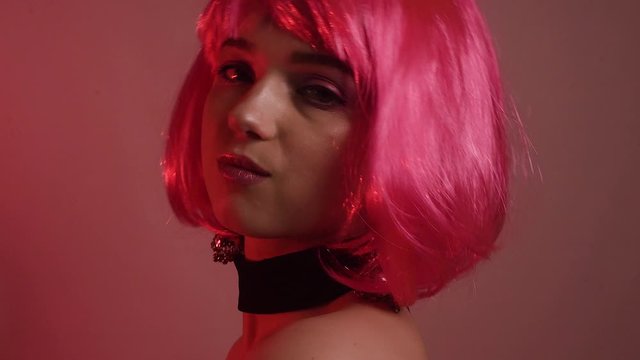 Girl with pink short hair. A model with long pink earrings and makeup. The girl in the video laughs, flirts, poses, dances, touches her hair, goes crazy. Fashion video portrait
