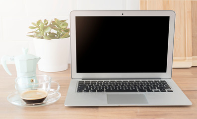 Fototapeta premium Home Office. Working From Home. Laptop With Blank Screen. Cup Of Coffee And Italian Coffee Maker In Blue. Bright And Clean Kitchen, Close Up. Cutting Boards, Green Succulent Pot On Wooden Worktop