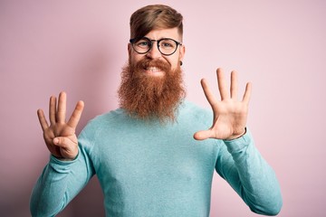 Handsome Irish redhead man with beard wearing glasses over pink isolated background showing and...