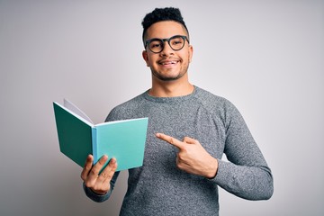 Young handsome smart student man reading book over isolated white background very happy pointing with hand and finger