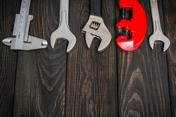 Big set of tools for a plumber on black wooden boards prepared by professional master before repair...