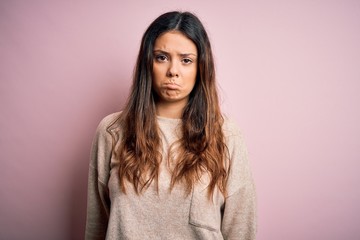 Obraz premium Young beautiful brunette woman wearing casual sweater standing over pink background depressed and worry for distress, crying angry and afraid. Sad expression.