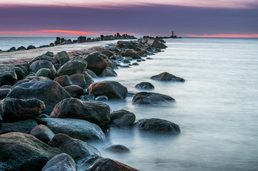 Long exposure of Baltic sea with scenic colorful sunset. Silky water motion and breakwater with...