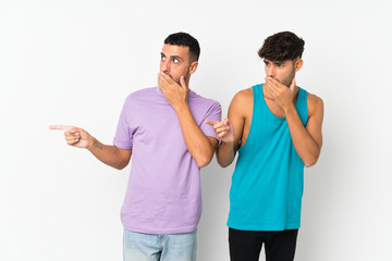 Two men over isolated background pointing finger to the side with a surprised face