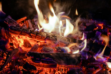 Burning firewood in the fireplace close up, BBQ fire, charcoal background. Charcoal fire with sparks
