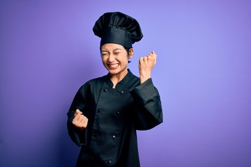 Young beautiful chinese chef woman wearing cooker uniform and hat over purple background celebrating surprised and amazed for success with arms raised and eyes closed. Winner concept.