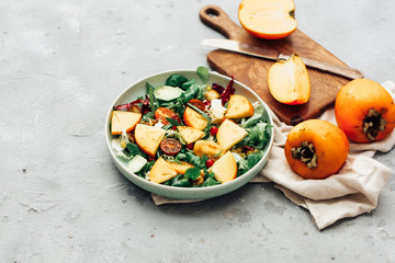 Fresh salad with fruits and greens on white wooden background close up. Healthy food.