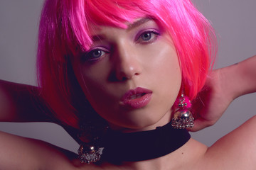 Portrait of a girl with pink hair and chic, fashionable  earrings, pink earrings with silver. Jewelry, accessories. Stylish girl in a checker and means. Girl with pink make-up. Professional makeup.