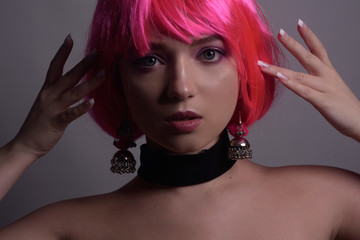 Fototapeta premium Portrait of a girl with pink hair and chic, fashionable earrings, pink earrings with silver. Jewelry, accessories. Stylish girl in a checker and means. Girl with pink make-up. Professional makeup.