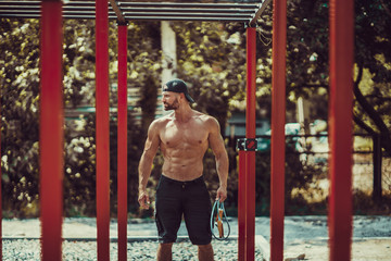 Bearded bodybuilder man exercising on monkey bars for the upper-body in a modern calisthenics park...