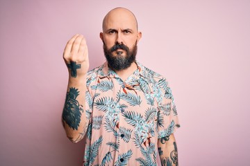 Handsome bald man with beard and tattoo wearing casual floral shirt over pink background Doing Italian gesture with hand and fingers confident expression