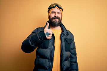 Handsome skier bald man with beard skiing wearing snow sportswear and ski goggles doing happy...