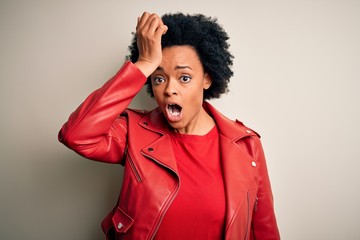 Young beautiful African American afro woman with curly hair wearing casual red jacket surprised...