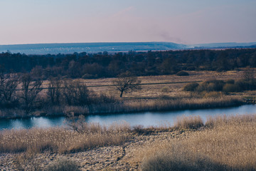 A quiet river in a green rural area. Beautiful landscape with a river with calm water, located next to a spring forest in nature
