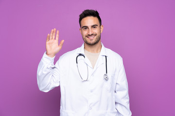 Young man wearing a doctor gown and saluting