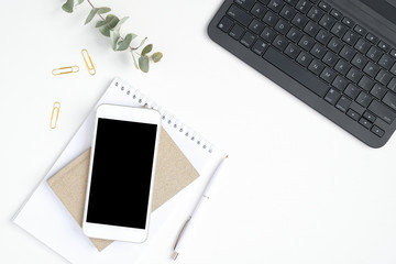 Female workspace with laptop computer keyboard, smartphone with blank screen mockup, paper notepad and notebook. Stylish home office desk table concept