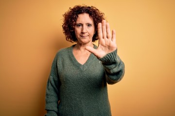 Middle age beautiful curly hair woman wearing casual sweater over isolated yellow background doing...