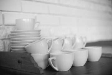Beautiful tea mugs and saucers stand on a wooden table in the kitchen at the cafe.
